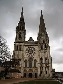 Photographie en couleurs de la façade d'une cathédrale gothique, sur fond de ciel plombé