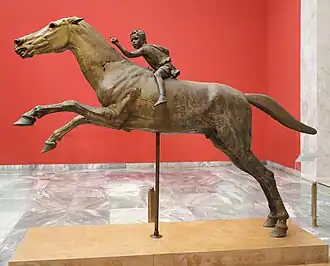 Statue en bronze monumentale d'un cheval avec un enfant sur son dos.