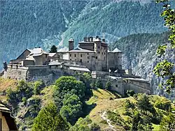 Un château-fort entouré de remparts de style Vauban, sur une butte dans une vallée de montagne.