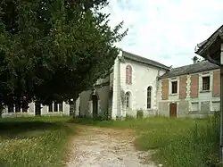Photographie en couleurs d'un bâtiment aux baies en plein cintre imbriqué dans d'autres constructions.