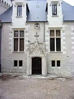 Photographie en couleurs d'un mur percé d'une porte dont les entourages sont très ouvragés.