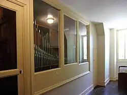 Photographie en couleurs d'une vitrine au travers de laquelle on voit de rangées de tuyaux verticaux.