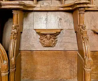 Deux accoudoirs sculptés entourent une miséricorde.