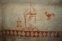 Vue de détail d'une pièce souterraine munie de fresques peintes en rouge