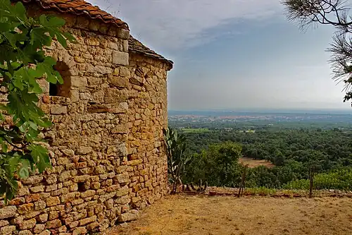 Vue de la face sud et de l'abside de Saint-Jérôme et, en arrière-plan, la plaine du Roussillon.