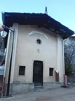 Photographie d'une chapelle : la porte en bois est dominée par une lucarne et des dessins religieux.