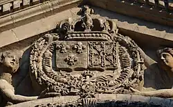 Le fronton, à gauche, les armoiries de la France «  d'azur à trois fleurs de lis d'or » et à droite, les armoiries de Navarre, le titre roi de France et de Navarre étant porté par le souverain français entre le XVIe&nbsp;siècle et la Révolution française.