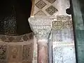 Vue d'un chapiteau du mihrab. En forme de tronc de cône renversé, il est coiffé d'un abaque richement sculpté, lequel est surmonté d'un mince bandeau épigraphique en caractères coufiques.