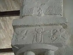 Chapiteau roman orné d'un personnage et d'oiseaux stylisés.