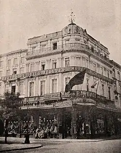 Photo noir et blanc d'un bâtiment de style haussmannien de quatre niveaux avec une coupole à l'angle