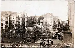 Photo noir et blanc de bâtiments en ruine avec des personnes passant à proximité