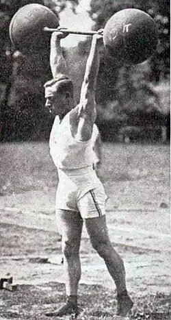 Photo d'un homme tenant des deux mais, bras tendus un haltère.