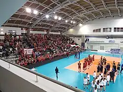 Une équipe de volleyball devant une tribune rempli de spectateurs.