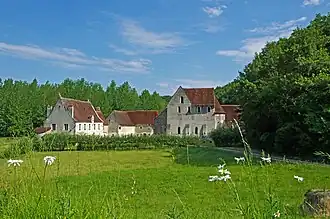 Photographie en couleurs d'un ensemble de bâtiments avec une forêt en second plan.