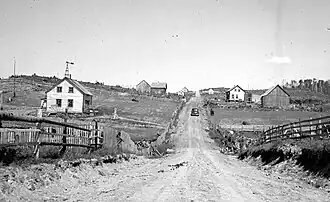 Un chemin de terre et des maisons de colons.