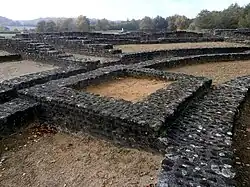 Photographie en couleurs d'une maçonnerie carrée au milieu d'autres murs incurvés.