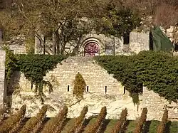 Photographie en couleurs d'un portail au centre d'un mur, au sommet d'un mur de soutènement.
