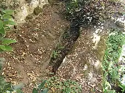 Photographie en couleurs d'un sarcophage creusé dans la roche du sol d'une chapelle.