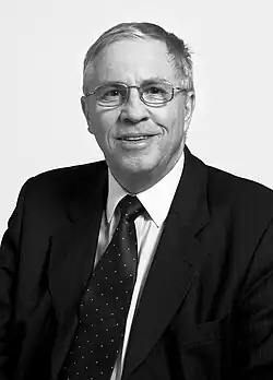 Portrait en noir et blanc d'un homme en costume portant des lunettes.