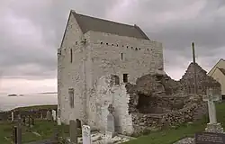 Photographie d'un bâtiment religieux intact, mais de petites dimensions, au milieu d'un cimetière