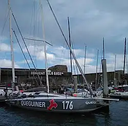 Vue latérale d'un voilier gris et blanc amarré au ponton.