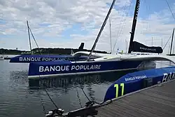 Vu de trois quarts avant, un trimaran géant amarré au ponton.