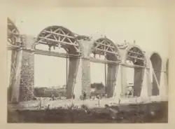Photographie en sépia montrant les structures en arc de cercle supportant les arches durant leur construction, trois cintres sont montés simultanément.