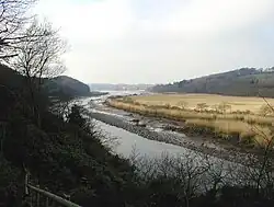 Des arbres au premier plan, puis la rivière dans une vallée élargie.