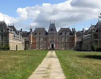 Grande bâtisse, de style Louis XIII, briques rouges, toit d'ardoise, trois étages, vue de loin, depuis le parc. Vue de la façade nord-ouest.