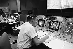 Clifford Charlesworth assis à sa console (vu ici de dos durant le vol Apollo 8).