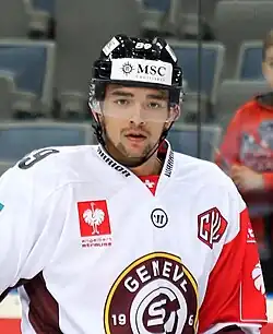 Hockeyeur de buste, de face, portant un maillot à dominante blanche, bouche entrouverte, regard fixe