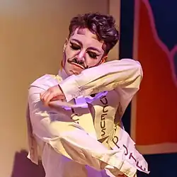 Drag king enlevant les étiquettes "suceuse" et "pute" agraphées à sa chemise