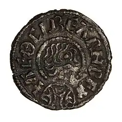 Photo d'une pièce de monnaie avec un visage de profil grossièrement dessiné entouré d'une inscription en lettres capitales