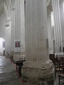 Photographie en couleurs de piliers dont la base, non alignée, est matérialisée par une ligne rouge rapportée.