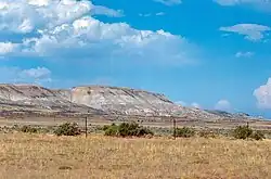 Une plaine agricole, à l'arrière-plan de grandes falaises roses.