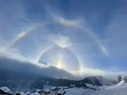 Un grand halo avec un arc circumzénithal, au dessus d'un halo de 22° doté d'un arc de Parry.