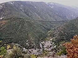 Le village de Conat dans la vallée de Caillan. La faille de Merens (ligne noire en pointillés) sépare les formations calcaires du Dévonien sur le versant opposé des formations cambriennes à dominance schisteuse sur le versant proche.