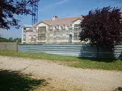 Photographie qui représente la construction d'un bâtiment avec un arbre sur le fond.
