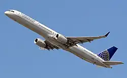 Vue du dessous d'un avion de ligne à réacteurs qui s'élève dans les airs.