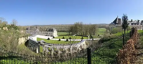 Vue panoramique vers la vallée de la Seille : le château à gauche, l'hémicycle au centre, les communs à gauche.
