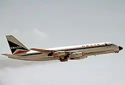 Photo couleur. Avion blanc aux bandes fines noires et rouges en montée, vu du côté droit.