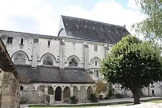Photographie en couleurs d'un grand bâtiment précédé d'une galerie couvert.