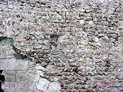 Photographie en couleurs d'un mur dont certaines pierres dessinent des chevrons.