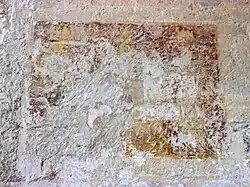 Photographie en couleurs d'une peinture à demi-effacée sur un mur.