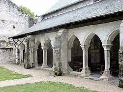 Photographie en couleurs d'une galerie à arcades de pierre couverte d'ardoises.