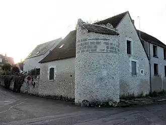 Photographie en couleurs d'un tour cylindrique ancienne accolée à un bâtiment moderne.