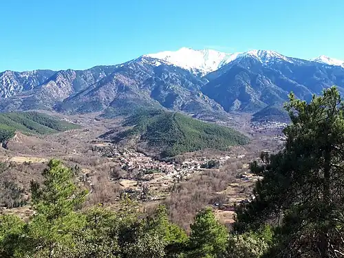 Village de Corneilla (au confluent des rivières Fillols (à gauche) et Cady (à droite), avec le Pic du Canigou (2785 mètres) en arrière-plan, au sud. La crête boisée qui s'élève derrière le village repose sur les dépôts du Miocène inférieur (c25 Ma) du bassin du Conflent.