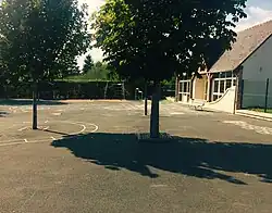 Photographie en couleurs d'une cour avec des dessins sur le sol goudronné.
