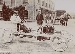 Photo d'un homme assis au volant d'une voiture sans carrosserie avec seulement les éléments mécaniques.