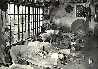 Vieille photographie montrant des émouleurs allongés en train d'émoudre leurs lames de couteaux.